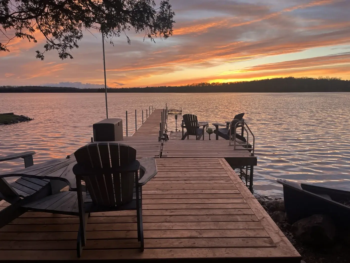A wooden dock reaching into a quiet lake at sunset